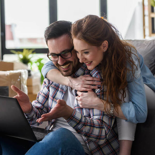 Happy couple looking at laptop, celebrating their fantastic mortgage deal